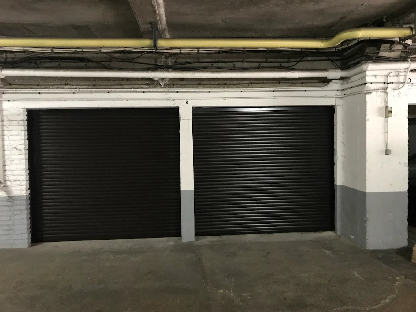 Rideaux métalliques noirs fermant deux box en sous-sol